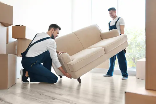 umzug-auszug-einziehen-karton-haus-07 Zwei Umzugshelfer mit Couch