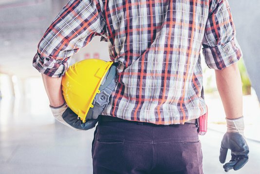 Handwerker mit Helm und Handschuhen im Inneren einer Baustelle.